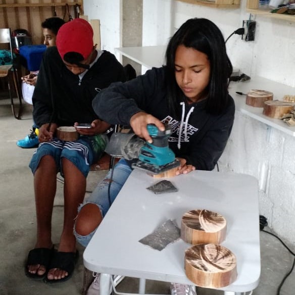 Adolescente manuseando lixadeira de madeira
