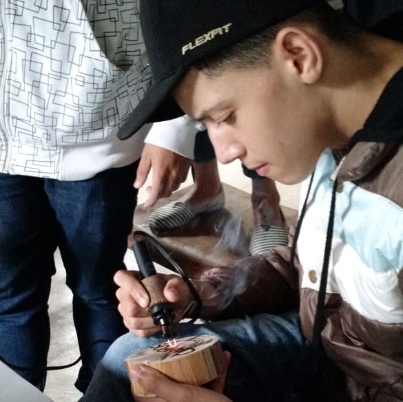 Adolescente escrevendo na madeira com pirógrafo